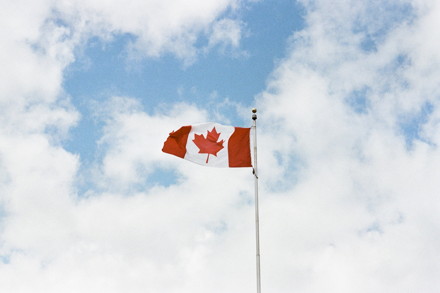 canada flag agianst blue & cloudy sky